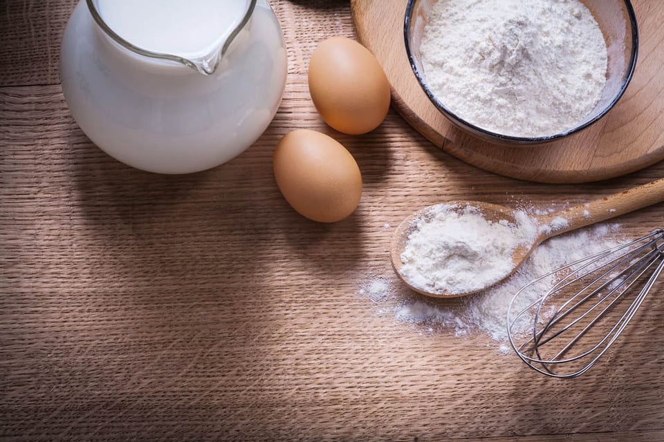 cómo hacer pizza, harina en un tazón, cuchara, jarra de huevos, con leche, mezclar