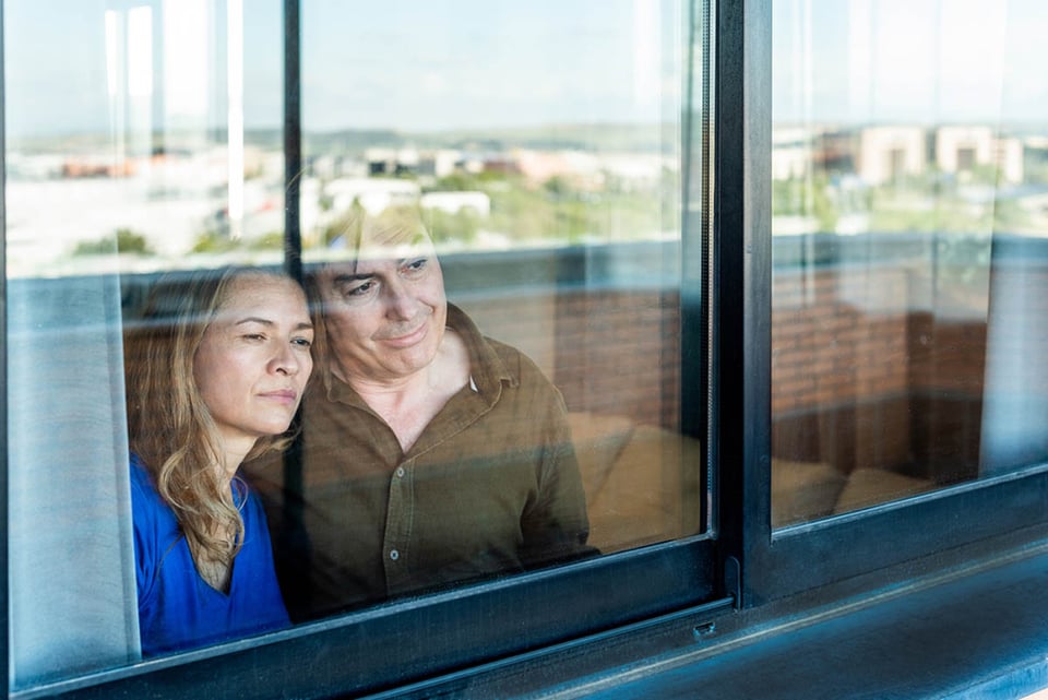 Pareja madura, mirando por la ventana, en casa, futuro, pensamientos
