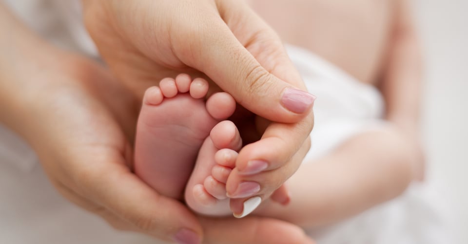 Pies de un bebé en manos de una persona