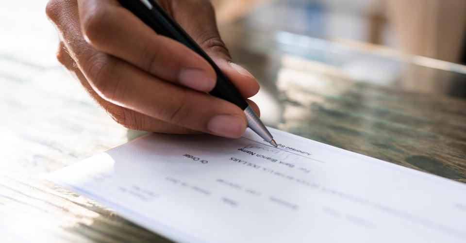Mano de persona firmando cheque de trabajo