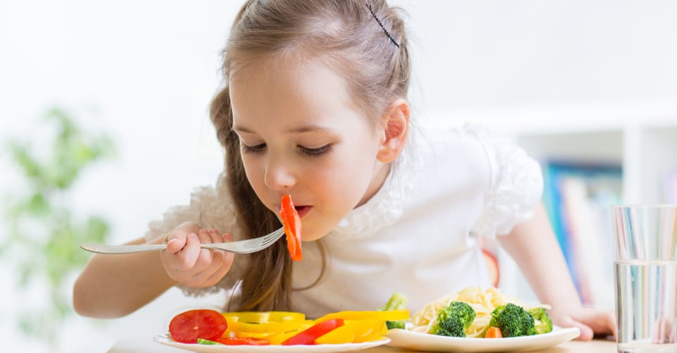 Plato con vegetales junto a un niña