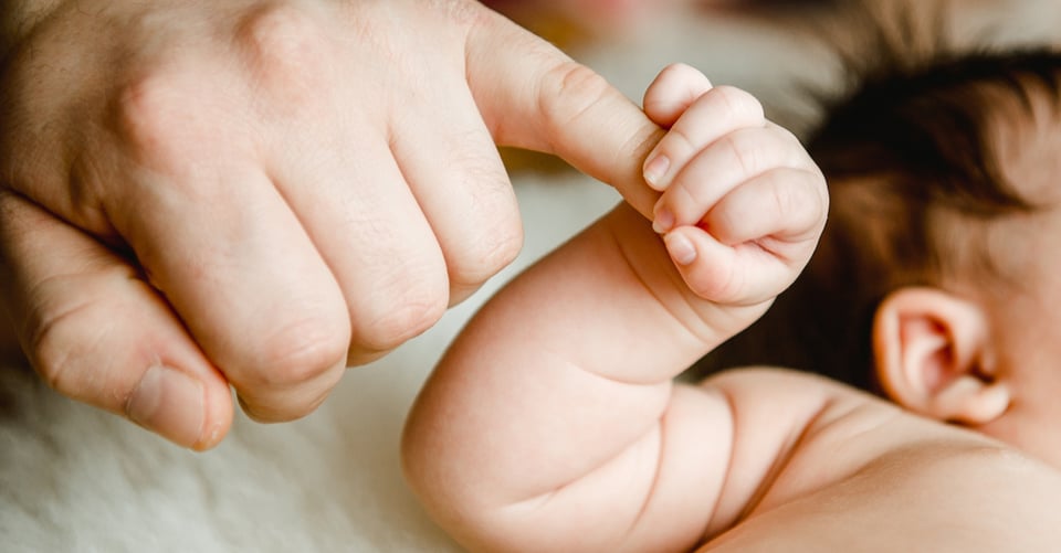 Mano de papá siendo sujetada por su bebé